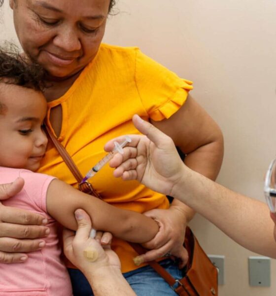 Profissional da saúde aplicando vacina em criança no colo da mãe em Jundiaí