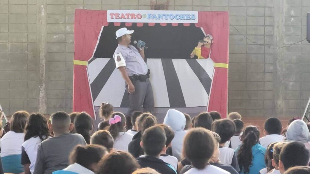 Policial ensina segurança no trânsito a crianças de Jundiaí em teatro de fantoches durante evento escolar educativo.