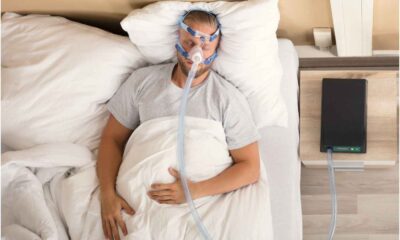 Homem deitado na cama, dormindo, usando aparelho para ajudar respirar durante apneia do sono