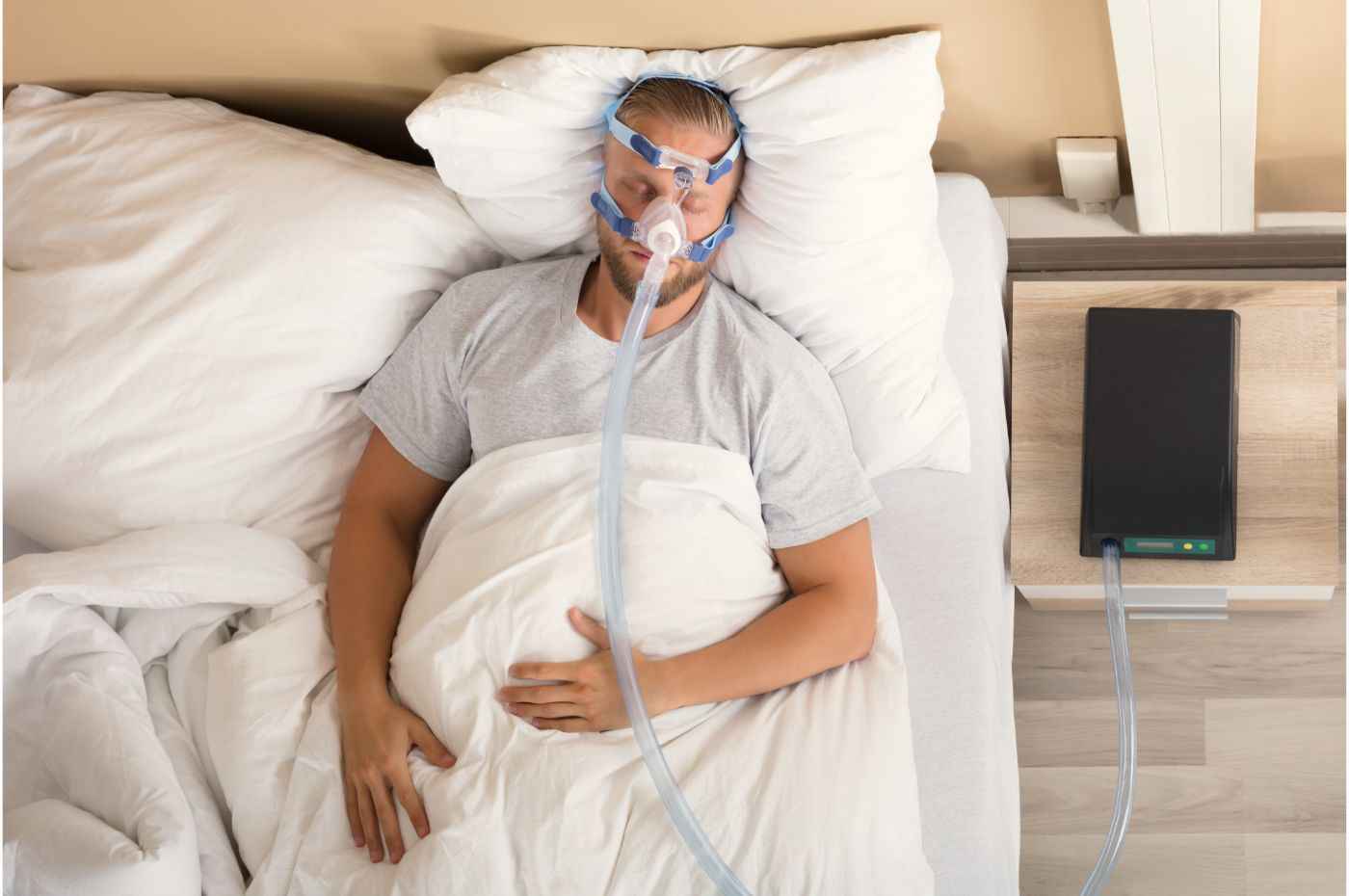 Homem deitado na cama, dormindo, usando aparelho para ajudar respirar durante apneia do sono