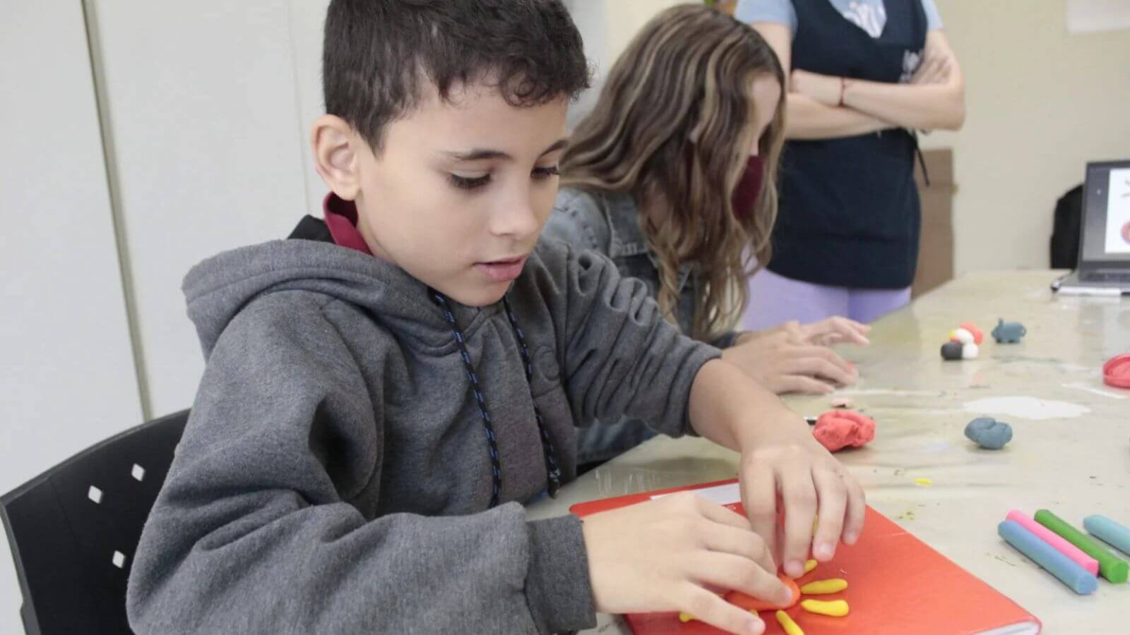 Criança em atividade de modelagem com massinha na APAE Jundiaí, desenvolvendo habilidades motoras e criatividade em ambiente educativo