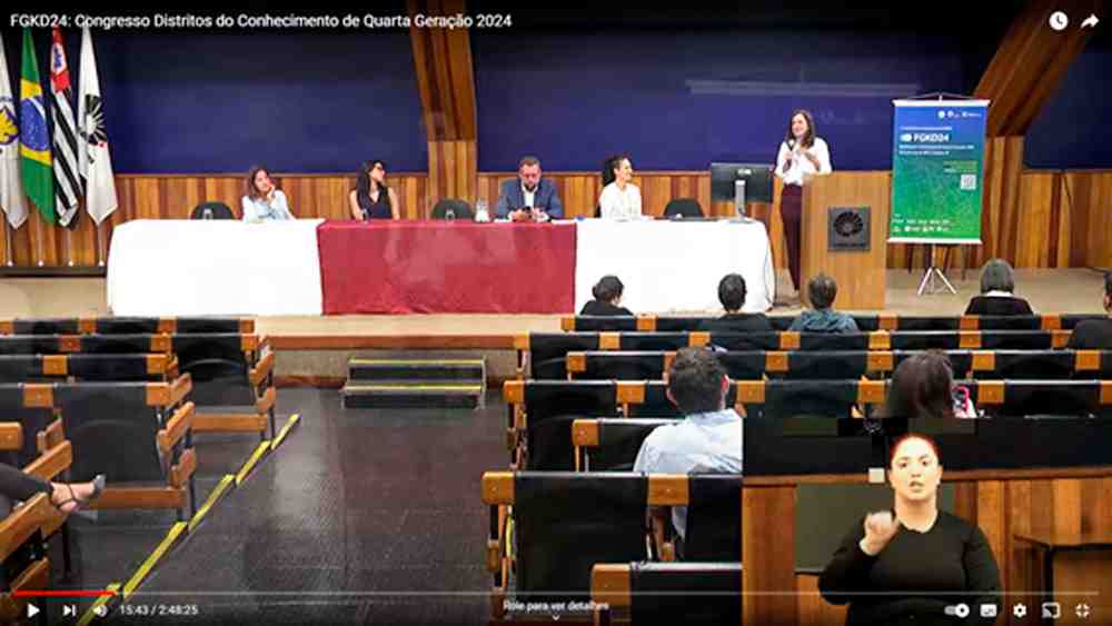 Conferência de urbanização na Unicamp com painel de cinco palestrantes, público assistindo e intérprete de Libras.