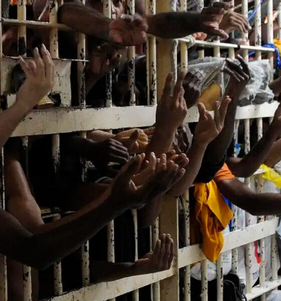 Cela superlotada de presídio, com vários detentos com os braços para fora das grades.