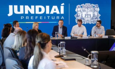 Autoridades de Jundiaí em reunião com representantes do Reino Unido sob um banner azul da prefeitura da cidade.