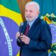 Presidente Lula falando ao microfone a frente da bandeira do Brasil