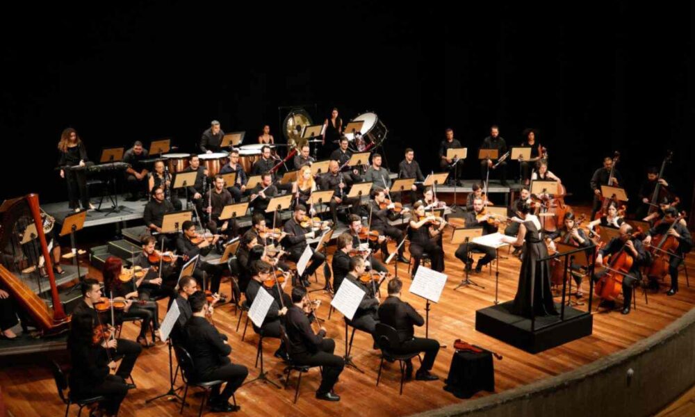 Grupo de pessoas com instrumentos musicais em cima de palco da Orquestra Sinfônica de Jundiaí