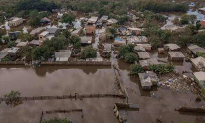 Bairro alagado após enchente, mostrando casas inundadas e danos causados pela água em uma comunidade do Rio Grande do Sul.