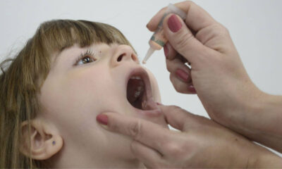 Criança recebendo vacina oral contra a poliomielite, conhecida como vacina contra paralisia infantil, em ambiente de saúde