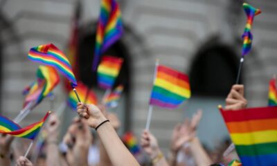 Pessoas levantando bandeira do Orgulho LGBTQIAP+