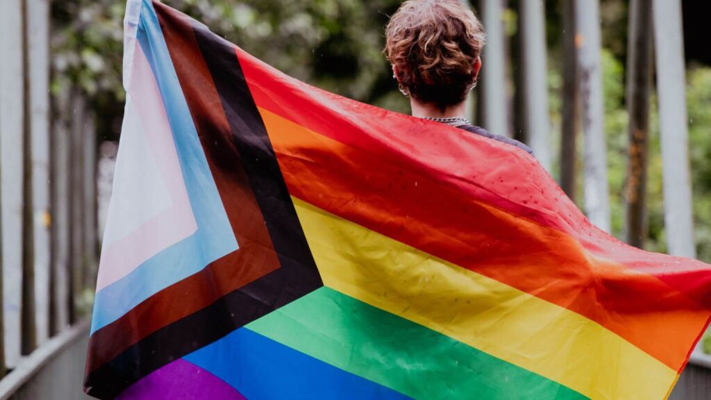 Pessoa segurando bandeira do Orgulho LGBTQIAP+