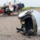 Acidente em Campo Limpo Paulista: capacete de motociclista no chão com moto caída ao fundo em estrada rural.