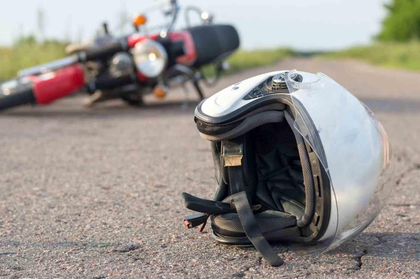 Acidente em Campo Limpo Paulista: capacete de motociclista no chão com moto caída ao fundo em estrada rural.