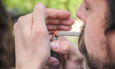 Homem acendendo um cigarro enrolado à mão com um isqueiro, relacionado à discussão sobre criminalização das drogas.