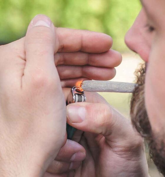 Homem acendendo um cigarro enrolado à mão com um isqueiro, relacionado à discussão sobre descriminalização do porte de drogas