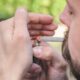 Homem acendendo um cigarro enrolado à mão com um isqueiro, relacionado à discussão sobre criminalização das drogas.
