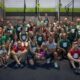 Grupo de pessoas reunidas em uma academia de CrossFit, identificada como CrossFit DaMata de Jundiaí. O grupo é composto por homens, mulheres e crianças.