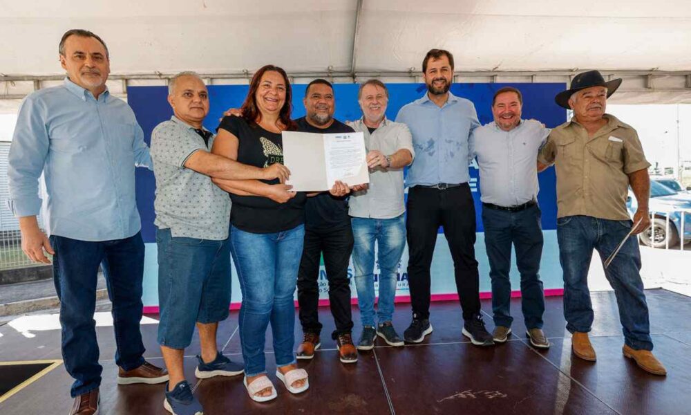 Entrega de escrituras no Jardim Novo Horizonte: Grupo de pessoas comemorando a regularização fundiária com documento oficial em mãos.