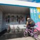 Imagem de uma mulher pegando uma bicicleta em uma bicicloteca de Jundiaí, que possui capacetes coloridos pendurados e bicicletas organizadas dentro de um contêiner decorado.