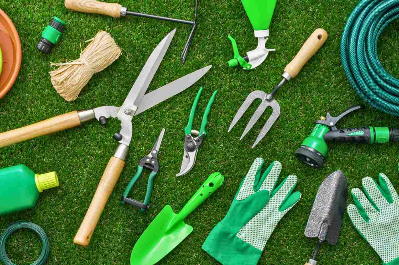 Diversas ferramentas de jardinagem espalhadas sobre a grama