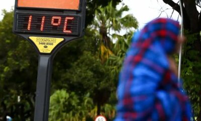 Temperaturas acima da média: Termômetro de rua mostra 11°C enquanto uma pessoa vestida com roupas de inverno caminha ao fundo.