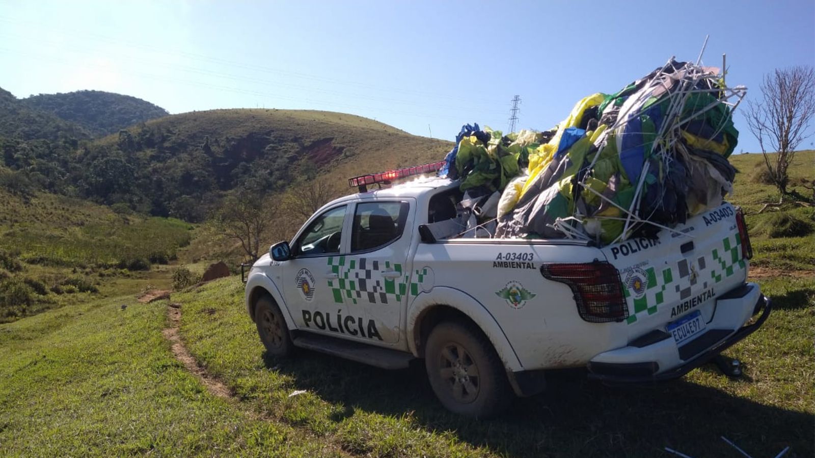 Caminhonete da Polícia Ambiental do Estado de São Paulo em uma área rural, carregando diversos balões desinflados e amassados na caçamba.