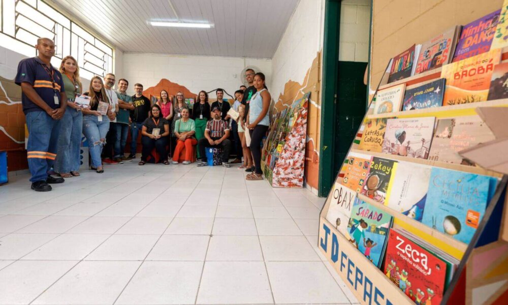 Grupo de pessoas, homens e mulheres, posando em uma sala, uma nova biblioteca comunitária