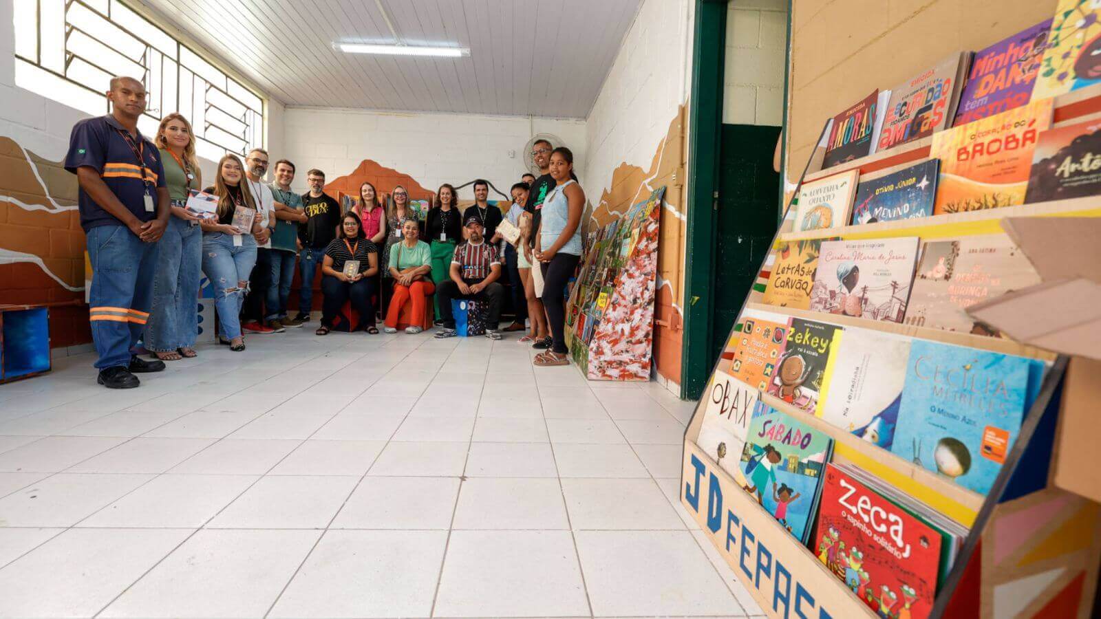 Grupo de pessoas, homens e mulheres, posando em uma sala, uma nova biblioteca comunitária
