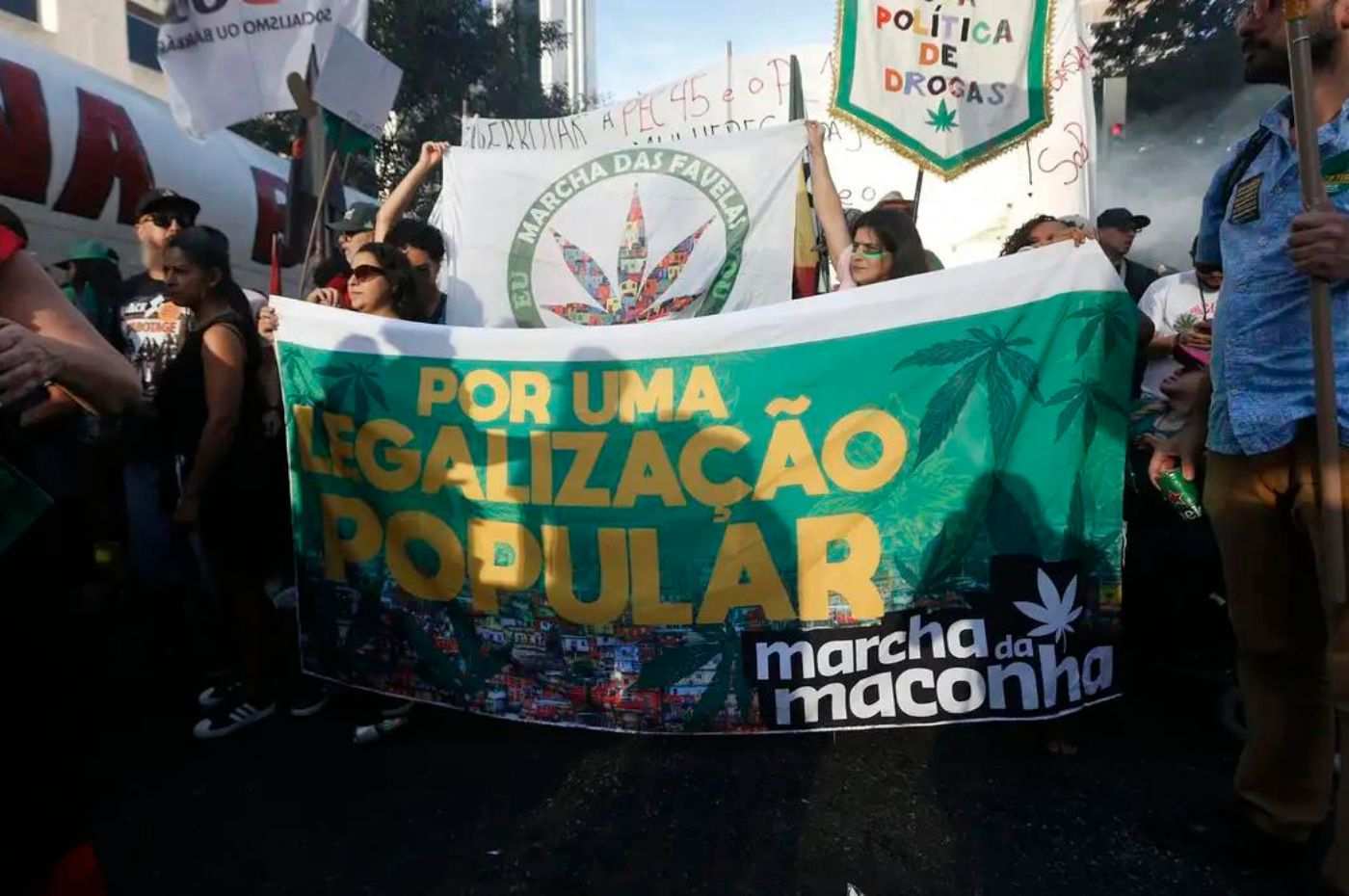 Manifestantes na Marcha da Maconha, segurando cartaz pedindo a legalização desta droga