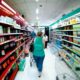Mulher fazendo compras em corredor de supermercado, simbolizando o impacto da inflação no custo dos alimentos para famílias.