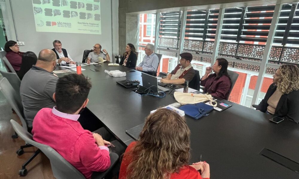 Reunião no Escritório de Projetos da Região Metropolitana de Jundiaí, com 11 pessoas sentadas ao redor de uma mesa grande, discutindo sobre projetos regionais de São Paulo.