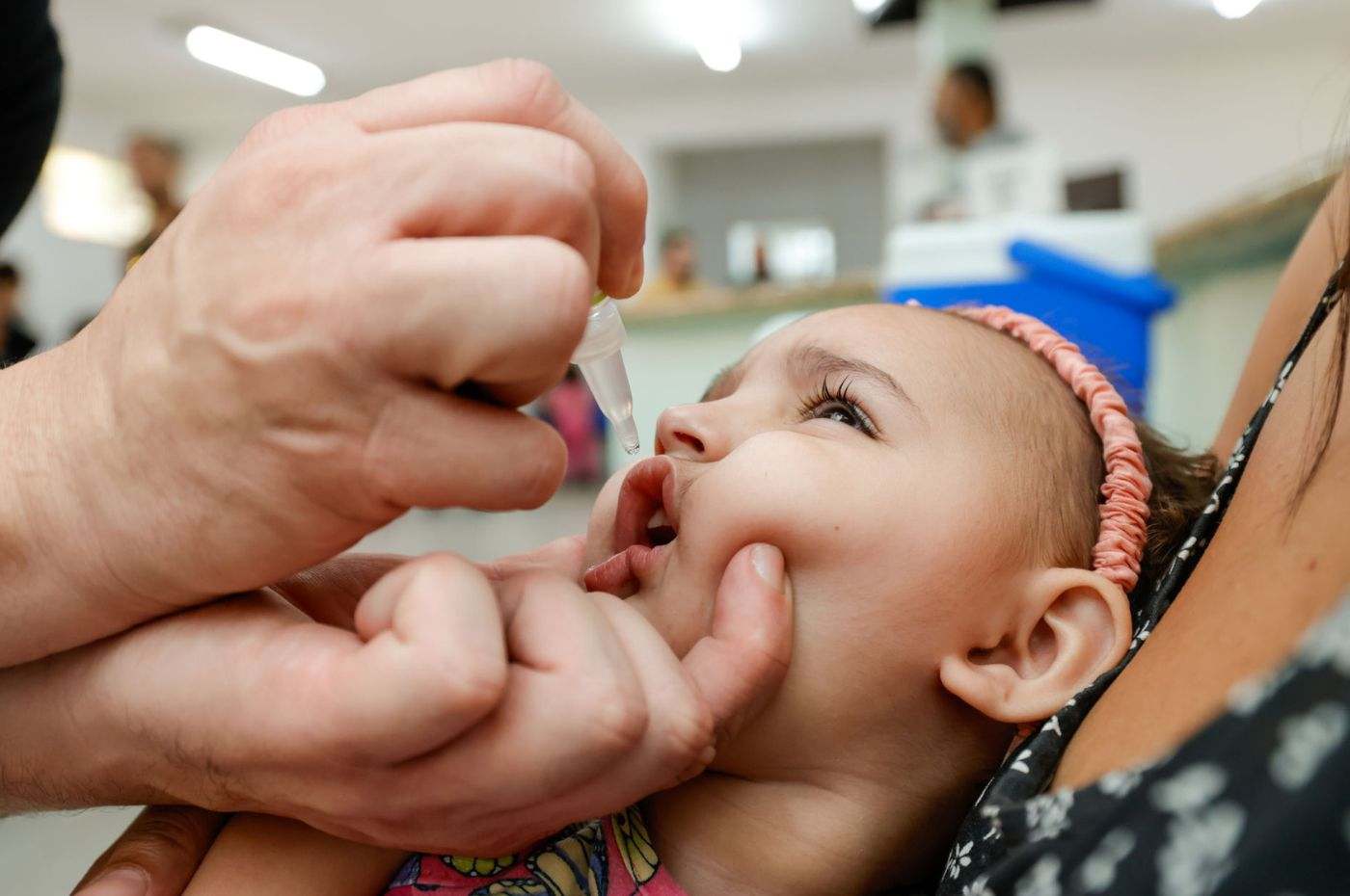 Criança tomando vacina da gotinha contra paralisia infantil