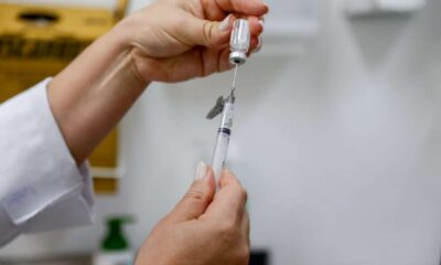 Profissional de saúde preparando seringa com vacina contra a dengue em Jundiaí, focada na imunização de crianças e adolescentes.