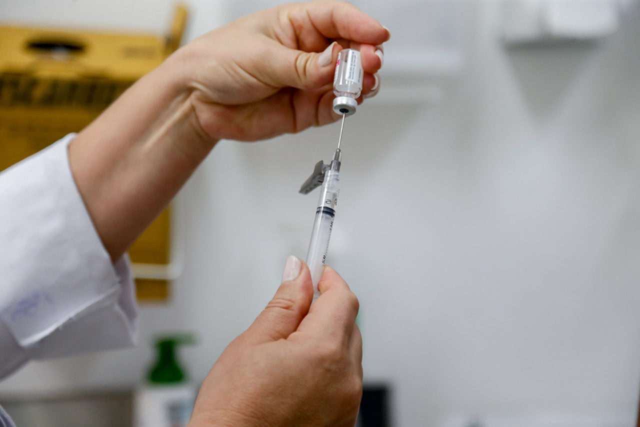Profissional de saúde preparando seringa para vacinação contra a dengue em Jundiaí.