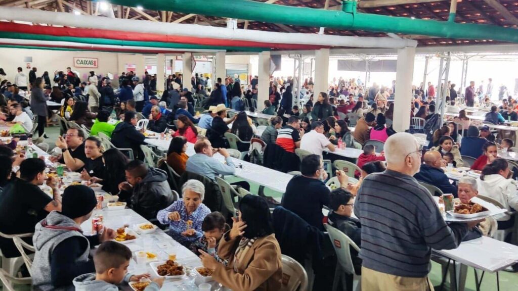 Praça de alimentação com muitas pessoas sentadas à mesa na Festa do Morango de Atibaia e Jarinu