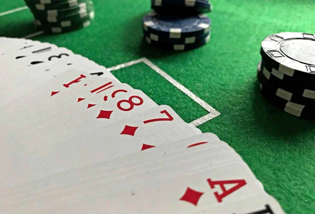 Mesa de cassino online com cartas de baralho e fichas de pôquer sobre um feltro verde.