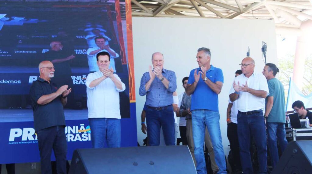 Dr. Luiz Braz e apoiadores em convenção política, aplaudindo no palco ao lado de líderes partidários, promovendo sua reeleição em Campo Limpo Paulista.