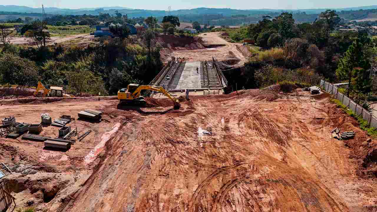 Obras em Jundiaí com escavadeiras e construção de ponte em área rural, mostrando progresso em infraestrutura viária.