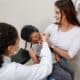 Mãe segurando criança enquanto profissional de saúde aplica Vacina contra a Paralisia Infantil em UBS