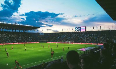 Estádio de futebol durante partida ao pôr do sol, perfeito para apostar em escanteios com análise detalhada do jogo.