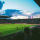 Estádio de futebol durante partida ao pôr do sol, perfeito para apostar em escanteios com análise detalhada do jogo.