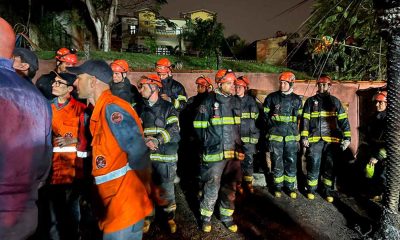 Equipe de bombeiros de SP reunida à noite em operação de resgate após acidente aéreo em Vinhedo, com uniformes e capacetes de segurança.