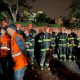 Equipe de bombeiros de SP reunida à noite em operação de resgate após acidente aéreo em Vinhedo, com uniformes e capacetes de segurança.