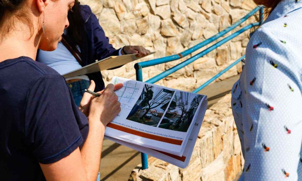 Técnicos da prefeitura de Jundiaí verificam obras de acessibilidade nas calçadas do Anhangabaú com plantas em mãos.