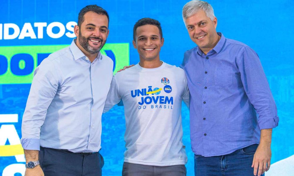 Gustavo Martinelli, Renan Peres e Ricardo Benassi sorrindo juntos em evento "Vozes da Cidade" em Jundiaí, com fundo azul e logo do União Brasil.