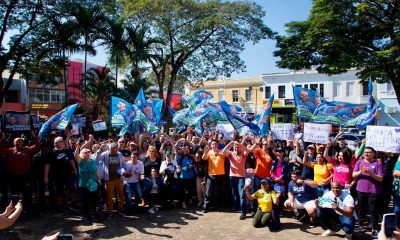 Gustavo Martinelli inicia campanha eleitoral no Centro de Jundiaí, cercado por apoiadores segurando bandeiras e cartazes.