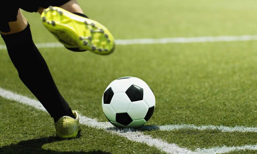 Jogador de futebol prestes a chutar a bola em um campo de grama durante jogo da Copa do Brasil.