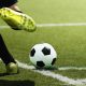 Jogador de futebol prestes a chutar a bola em um campo de grama durante jogo da Copa do Brasil.