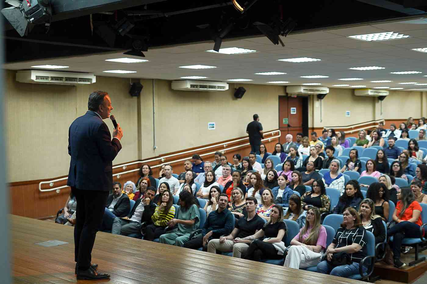 Parimoschi discursando para um auditório cheio de pessoas atentas durante evento sobre políticas para a infância em Jundiaí.