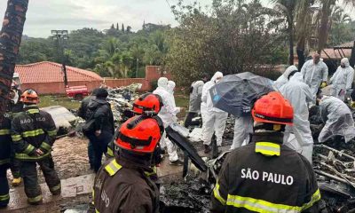 Equipes de resgate trabalham na remoção de vítimas após acidente aéreo em Vinhedo, com bombeiros e peritos no local.