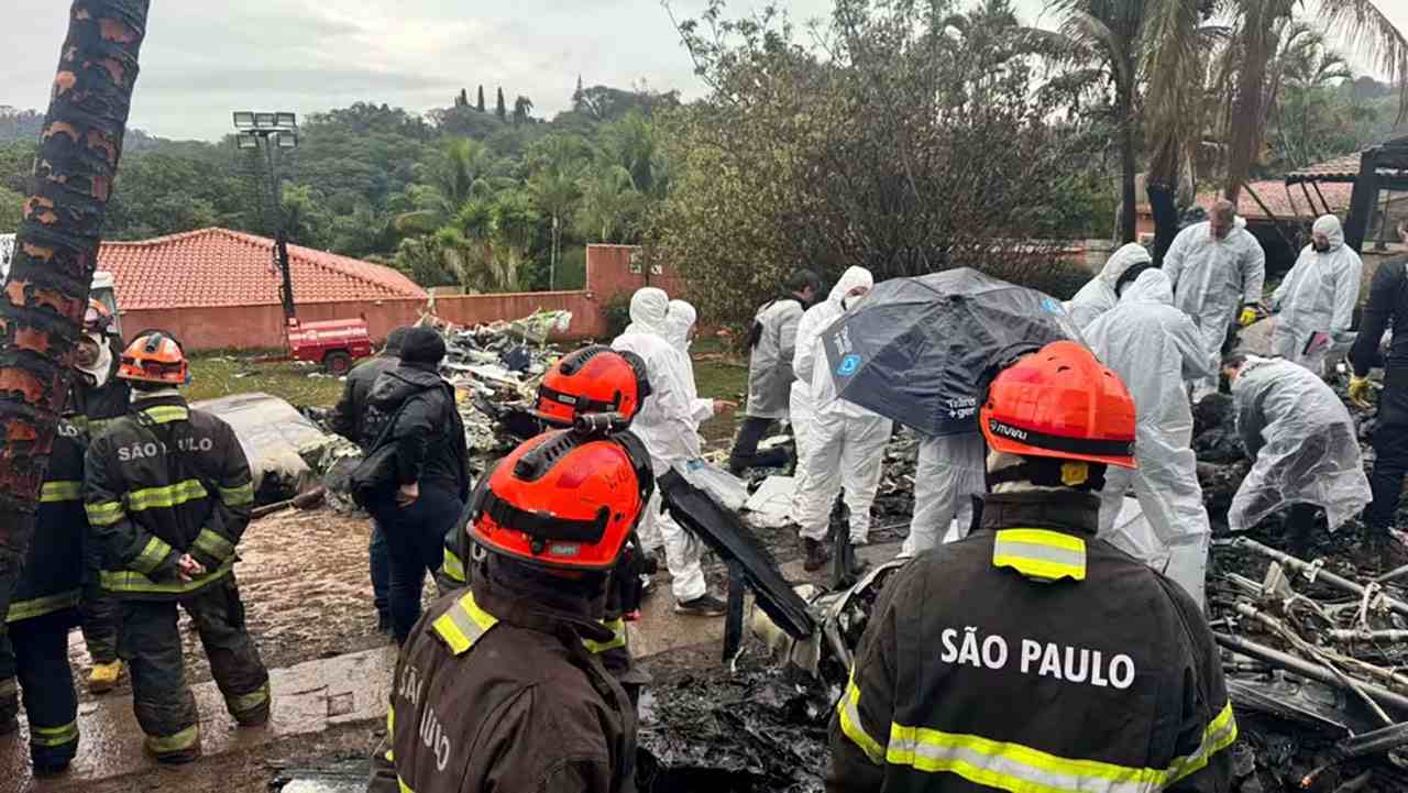 Equipes de resgate trabalham na remoção de vítimas após acidente aéreo em Vinhedo, com bombeiros e peritos no local.